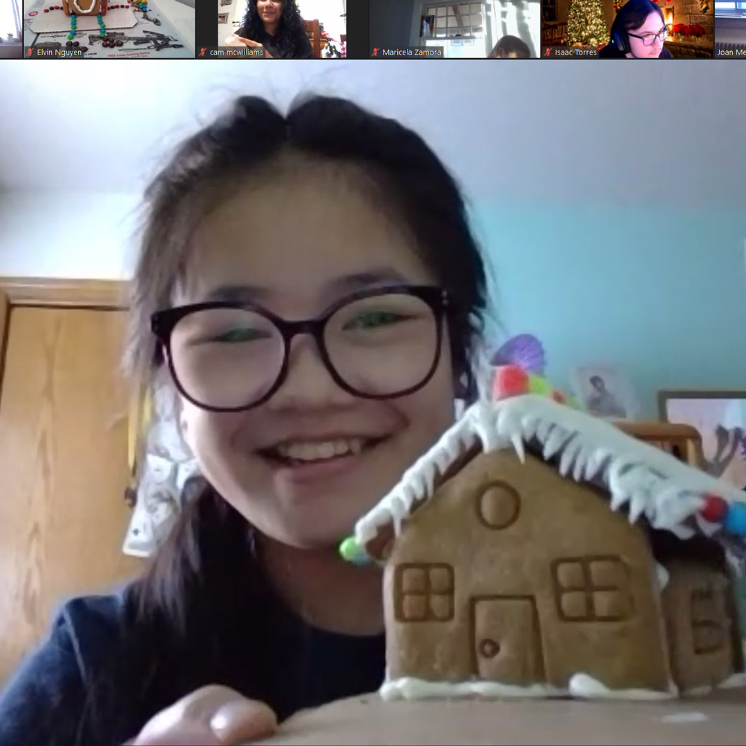 Student on Zoom holds gingerbread house