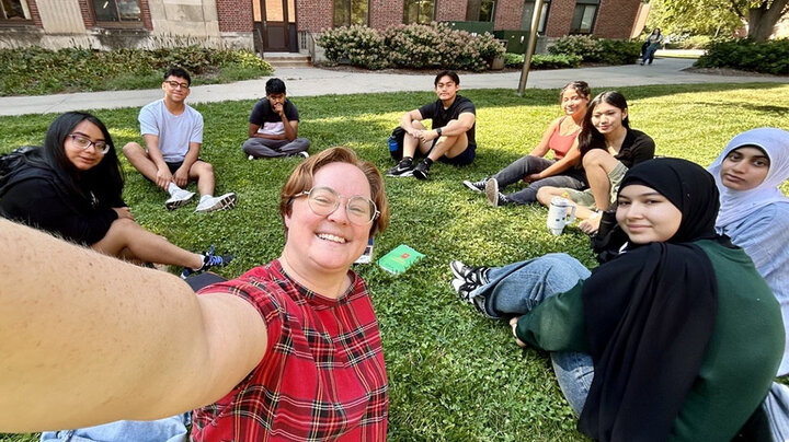 Students in a TRIO English Course sit outside in the grass. 