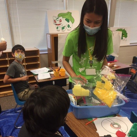 Student helps pass out summer projects in a classroom