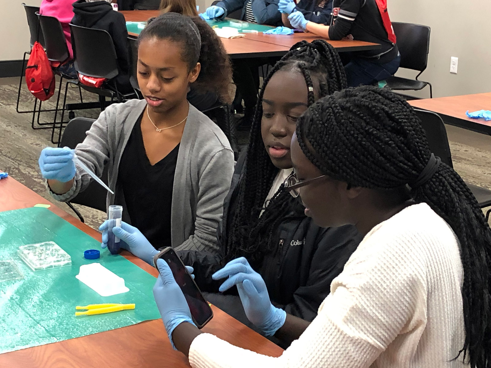 Three students use a pipette in a group project