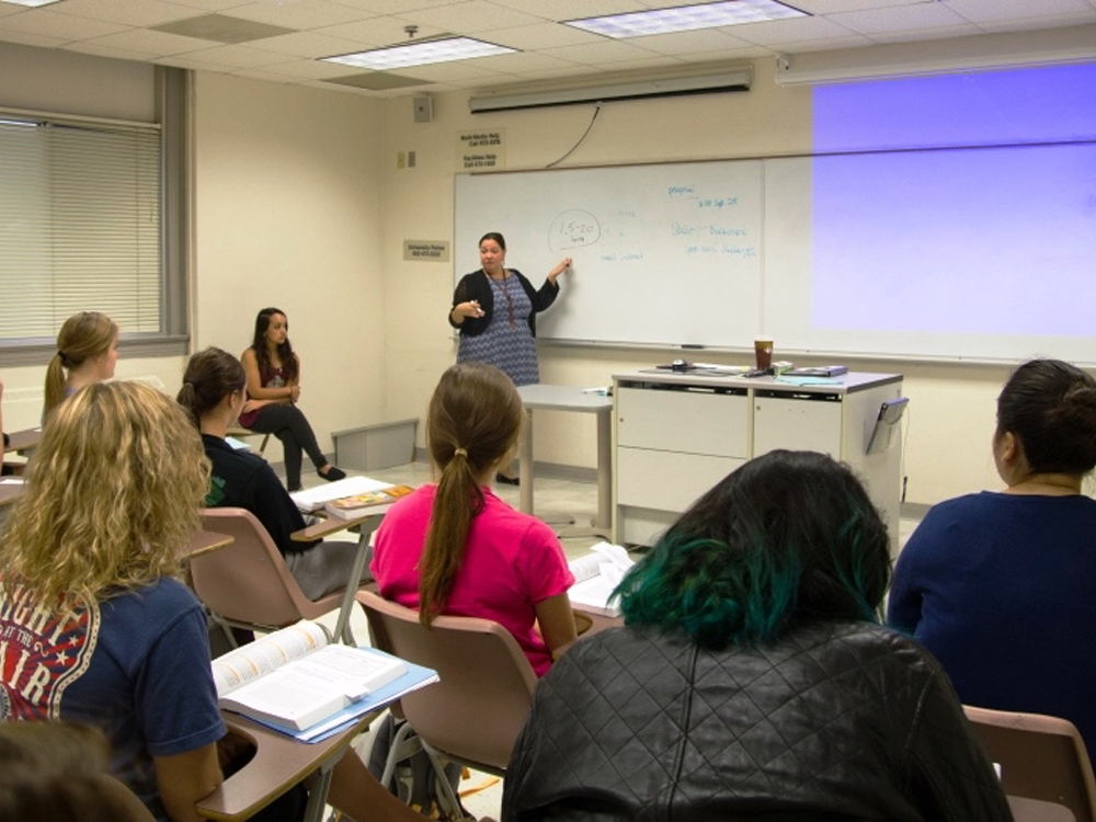 A young woman gesturing at a projected slide presentation